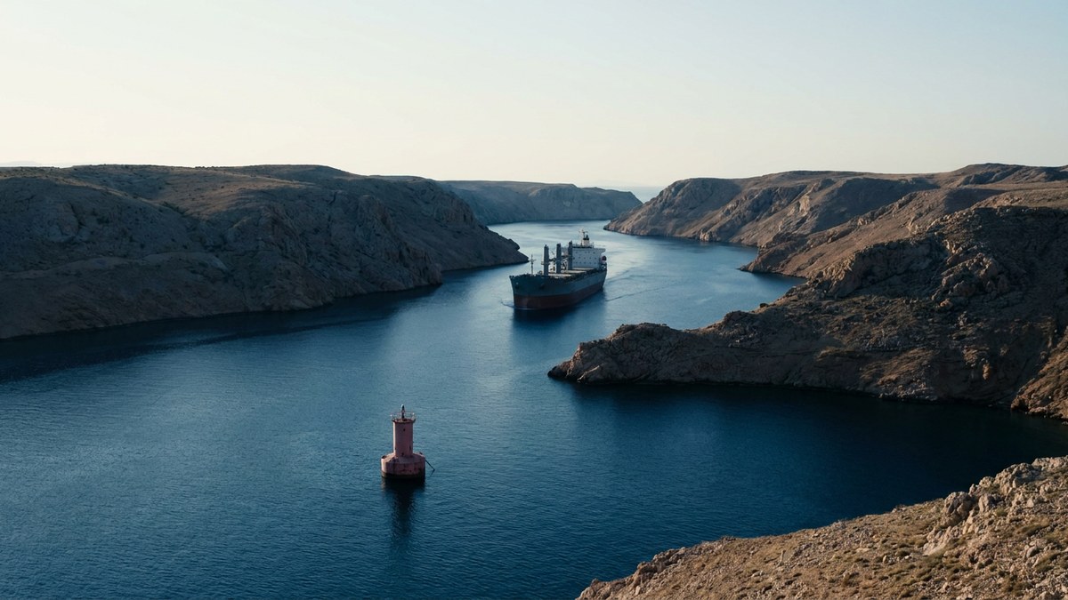 Illustrative cargo vessel moving through an arid coastal sea corridor
